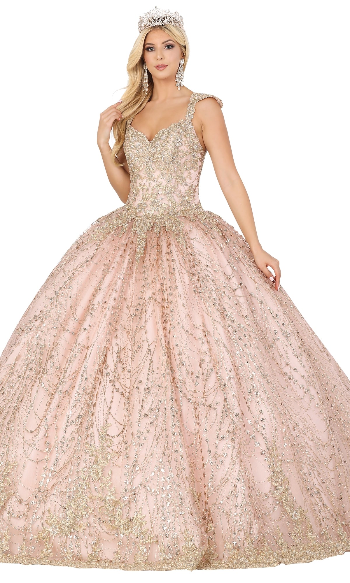A woman poses gracefully against a white background in Dancing Queen’s Quinceanera Dress 1478—a sparkling light pink ball gown with gold embellishments, cap sleeves, jeweled tiara, and large earrings.